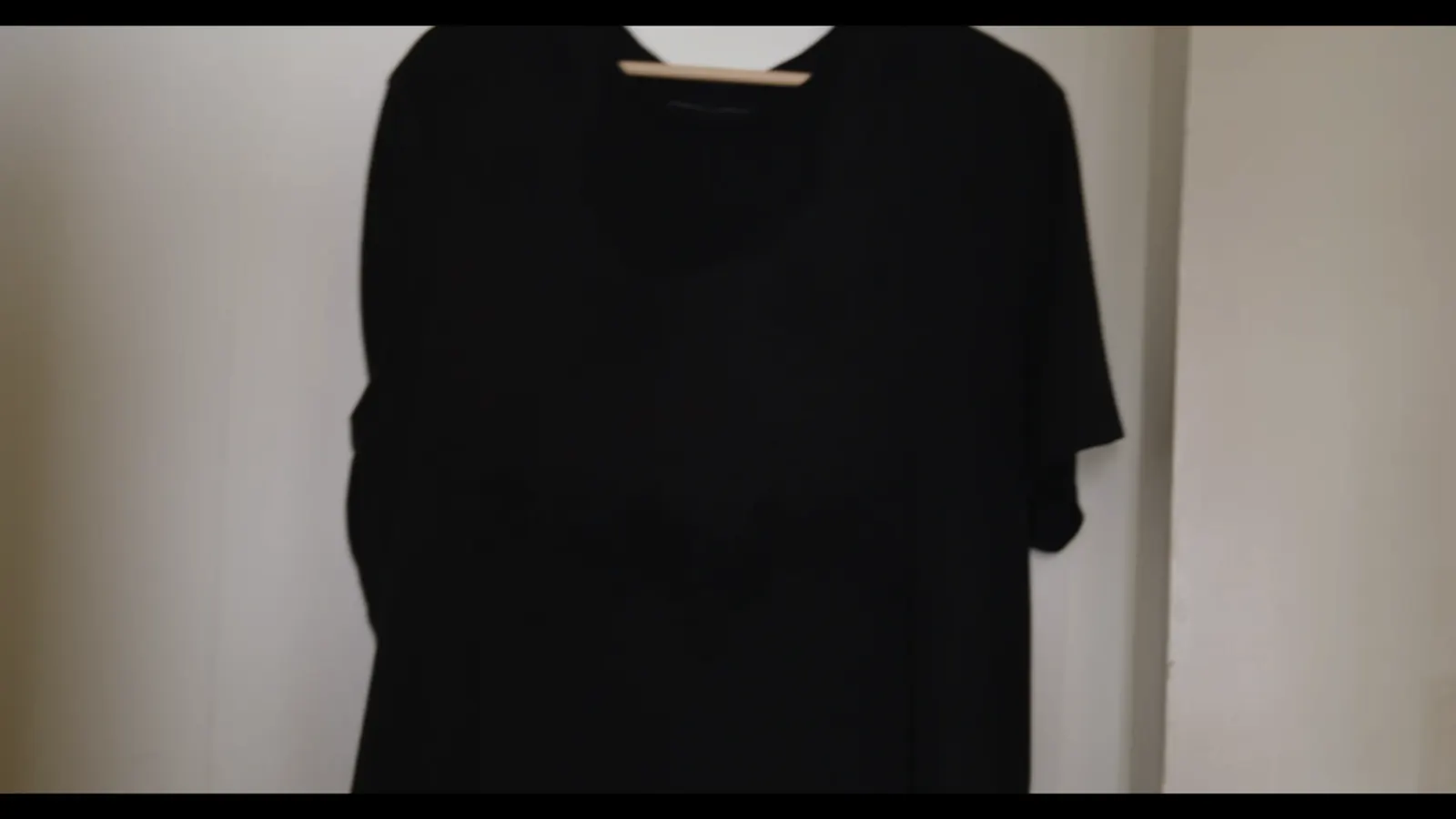 A black shirt on a hanger in low light.