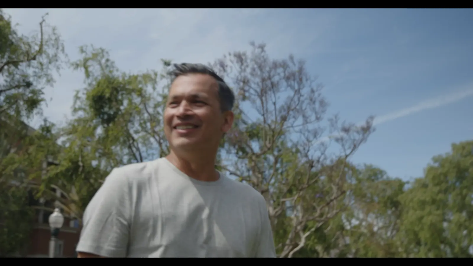 Walking in a white HyperNatural tee under trees.